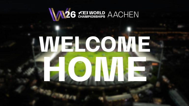 In einer Nachtaufnahme eines beleuchteten Stadions sind die Worte „WELCOME HOME“ in großen weißen Buchstaben zu sehen. Das Logo der FEI World Championships Aachen 2026 ist in der oberen linken Ecke zu sehen.